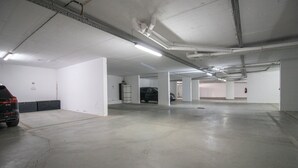 A parking garage with concrete floors, white walls, and a black SUV parked in one of the spaces.