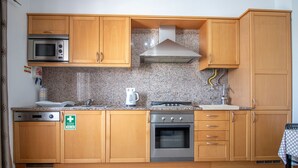 A kitchen with wooden cabinets, a microwave, an oven, and a coffee maker.