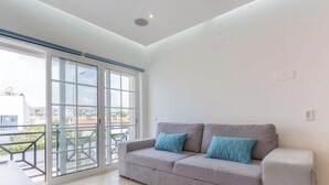 A modern living room with a grey sofa, two patterned cushions, and a large sliding glass door leading to a balcony. - #104 Fanichi Flat by Home Holidays (Albufeira)