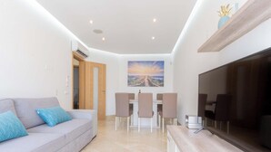 A modern living room with a sofa, TV, and dining area. - #104 Fanichi Flat by Home Holidays (Albufeira)