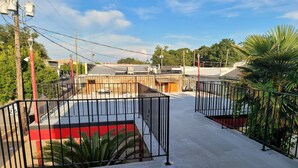 A rooftop parking area with a red and black fence, surrounded by greenery and buildings. - Relax inn (Lucedale)