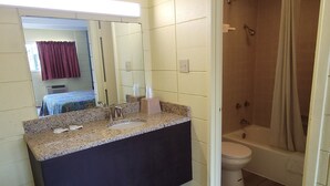 A bathroom with a granite countertop sink, a toilet, and a shower. - Relax inn (Lucedale)