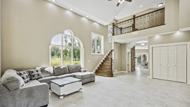 A spacious living room with a sectional sofa, a coffee table, and a staircase leading to an upper level. - Exceptional Getaway for Family & Friends (Rush City)