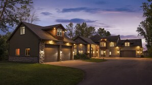 A multi-story residential building with a stone facade, multiple garage doors, and a driveway leading to the entrance. - Exceptional Getaway for Family & Friends (Rush City)