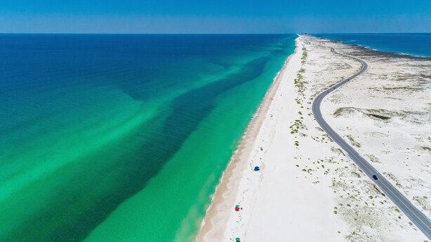 Vista aérea de una playa con una carretera que discurre paralela a la orilla.