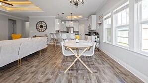 Una cocina moderna con armarios blancos, un refrigerador de acero inoxidable y un comedor con una mesa redonda y sillas.