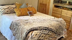 Un dormitorio con cama, techo de madera y una zona de cocina con armarios y encimera.