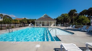 Una piscina con indicador de profundidad de 3 pies, rodeada de sillas de descanso y palmeras.