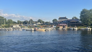 A marina with boats docked, a building with a covered area, and a clear sky. - Lovely waterfront 2 bedroom apartment (New Franklin)