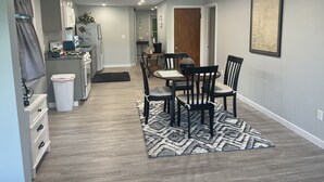 A modern kitchen with built-in appliances, a dining area with a rug, and a framed map on the wall. - Lovely waterfront 2 bedroom apartment (New Franklin)