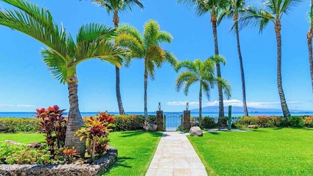 A pathway leading to a gate with palm trees and a view of the ocean. - Legal STR Hotel Zoned Lahaina Shores Serene Beachfront Escape with Mountain View (Lahaina)