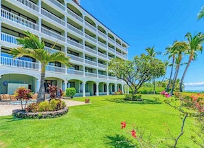 A multi-story hotel with a central courtyard, palm trees, and a pool area.