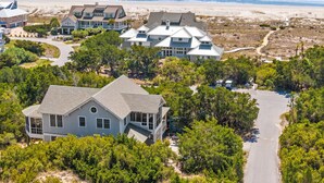 A coastal residential area with multiple houses, a road, and a beach in the background.
