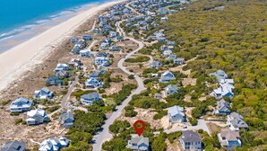 An aerial view of a coastal residential area with houses, a beach, and a road.