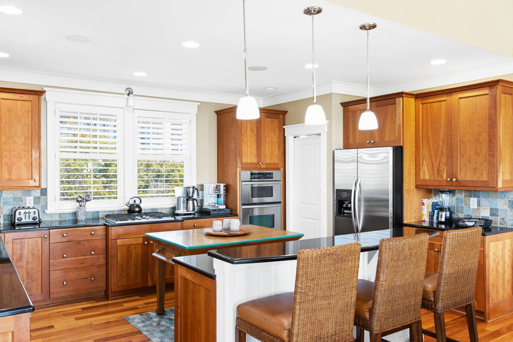 A modern kitchen with wooden cabinets, stainless steel appliances, and a central island with seating.