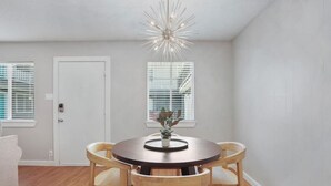 Un coin repas comprenant une table ronde, quatre chaises en bois, une plante en pot et un luminaire moderne au plafond.