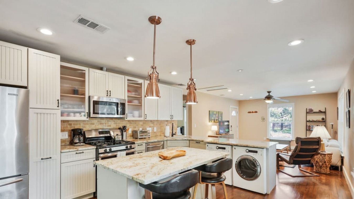 A modern kitchen with white cabinets, stainless steel appliances, and a central island with stools.