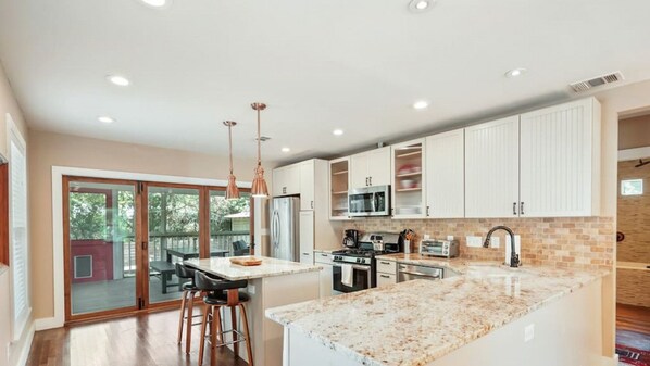 A modern kitchen with white cabinets, a granite countertop, and stainless steel appliances.