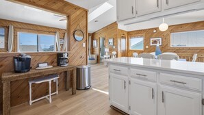 Uma cozinha moderna com paredes de madeira, armários brancos e uma ilha central.
