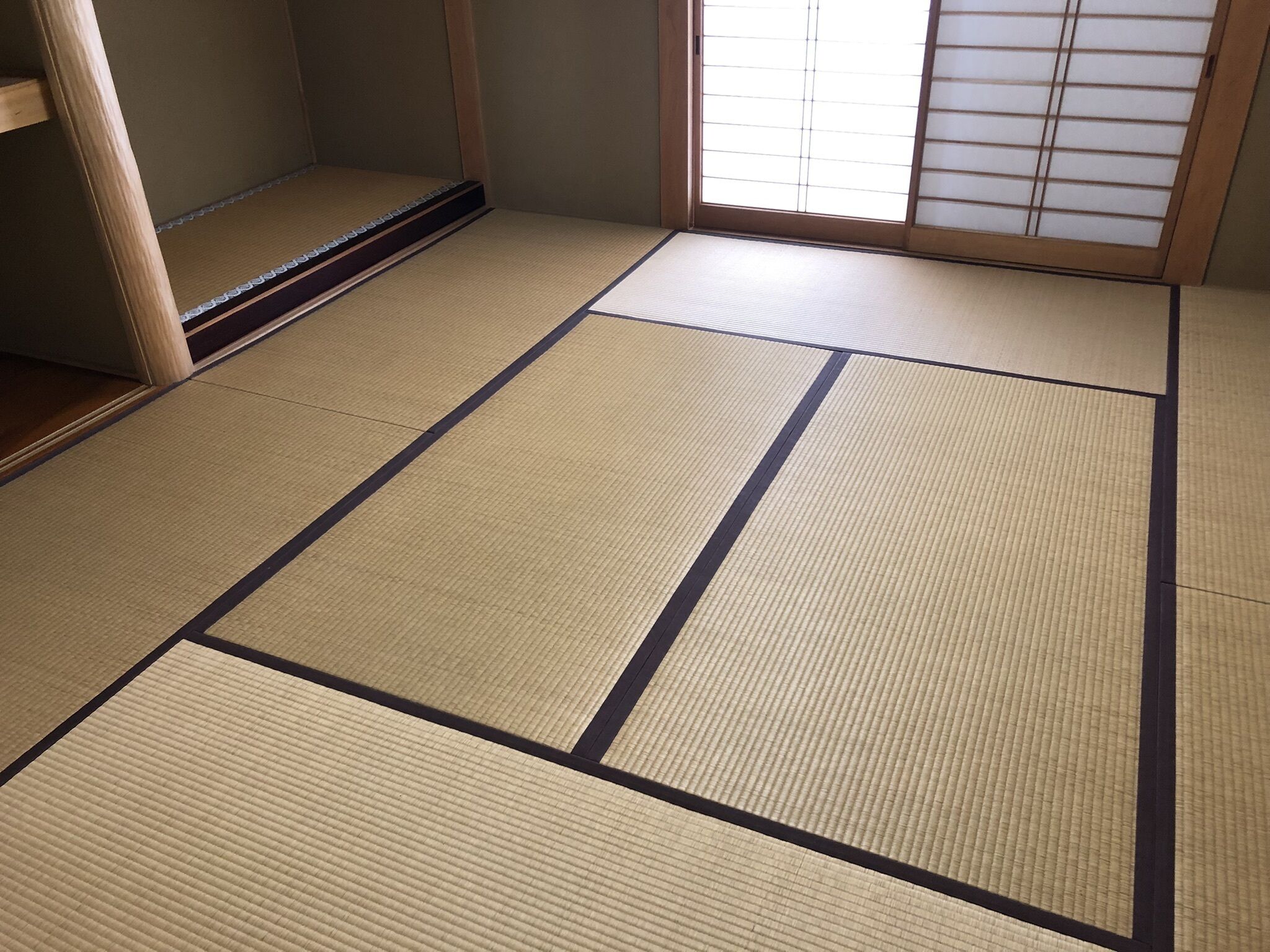 A tatami mat room with a sliding door and a window with shoji screens.
