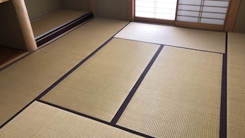 A tatami mat room with a sliding door and a window with shoji screens.