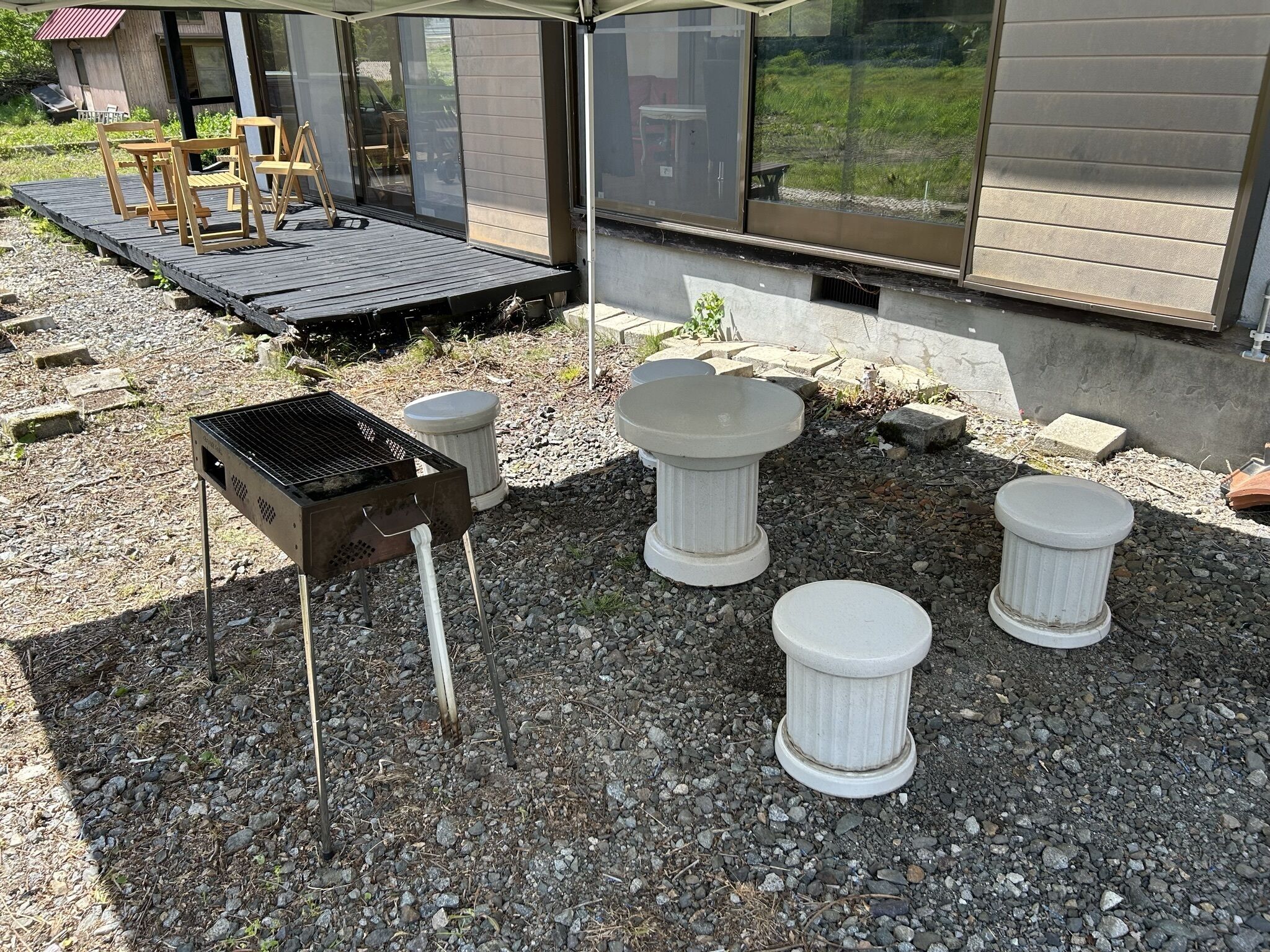 An outdoor patio area with a grill, stone planters, and a wooden deck.