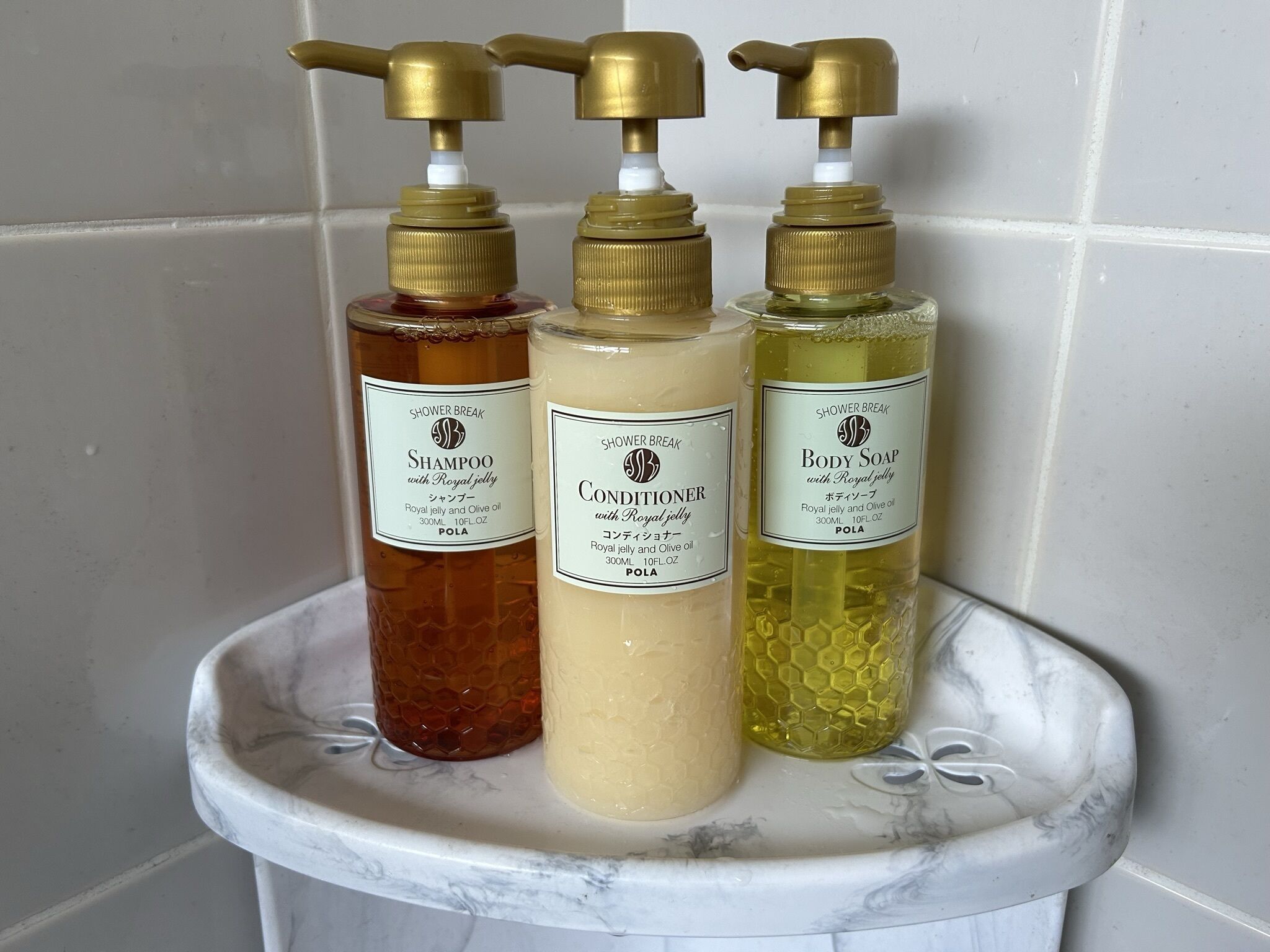 Tres botellas de productos de baño sobre un estante de mármol.