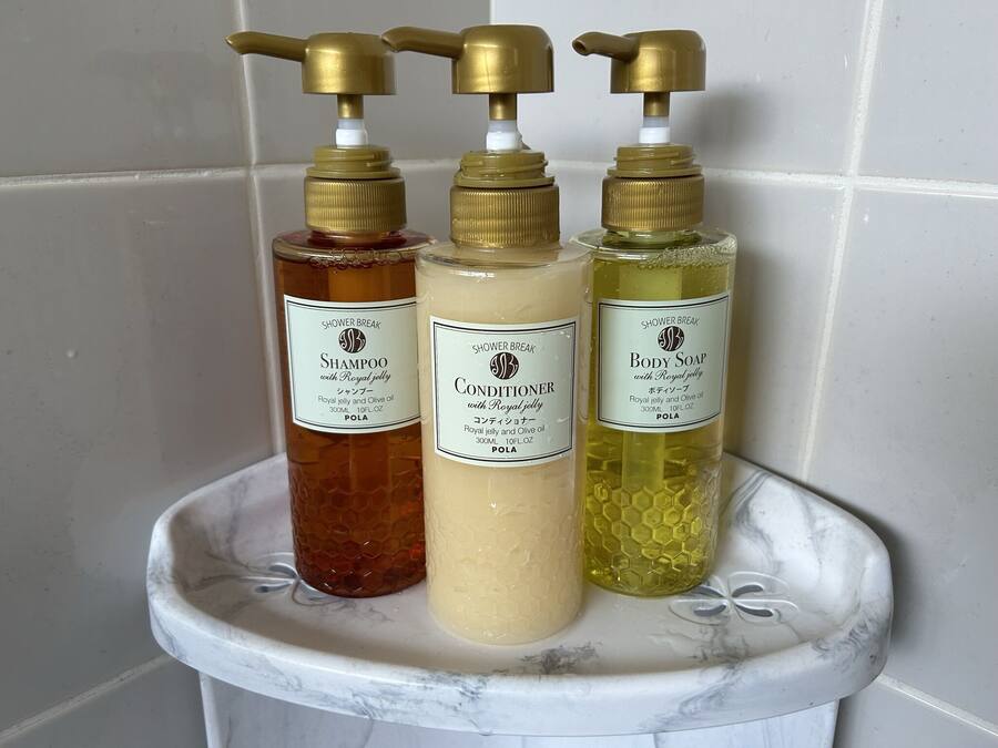 Three bottles of shower break products on a marble shelf.