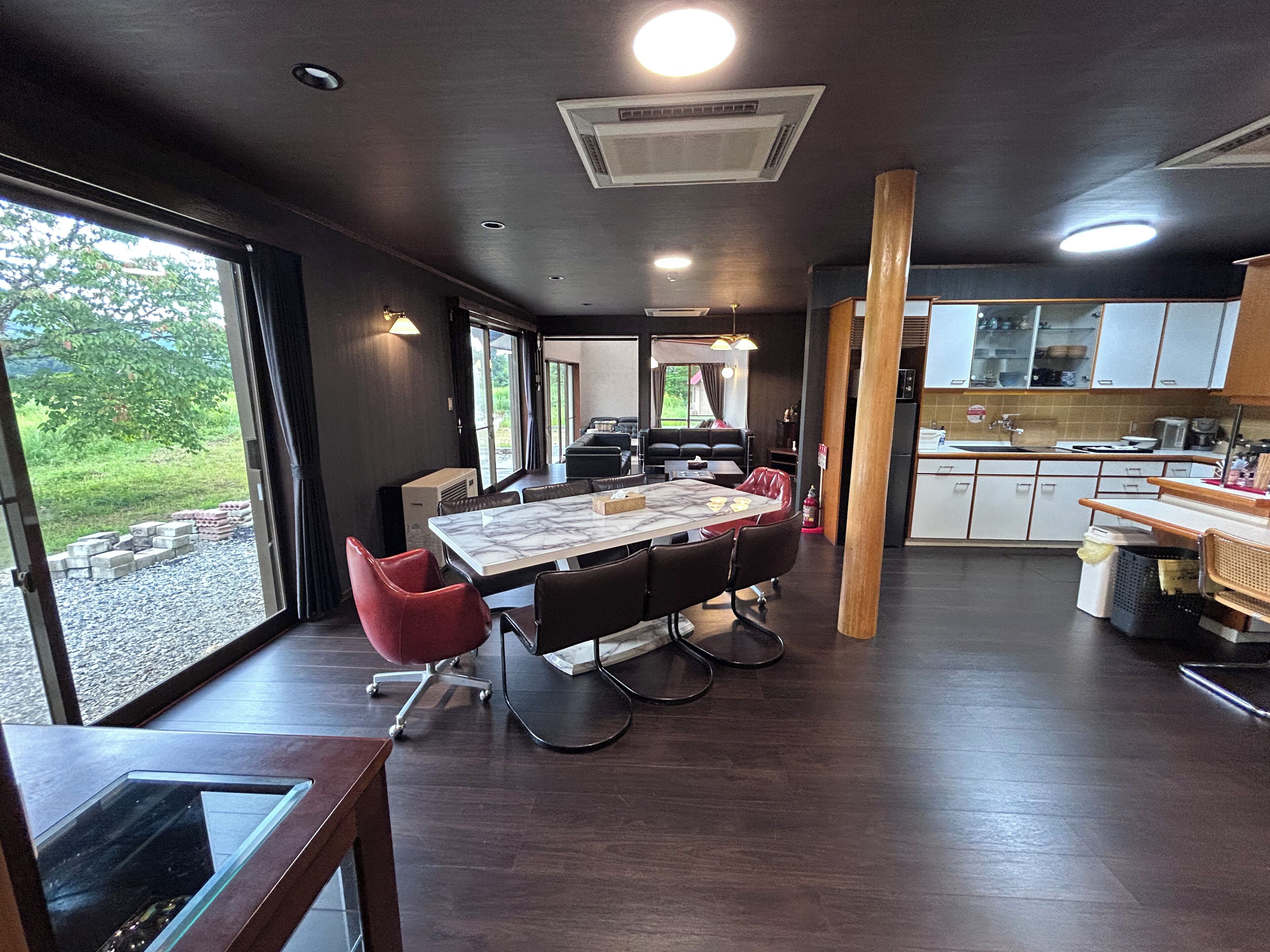 A modern kitchen with a dining area, large windows, and a view of the outdoors.