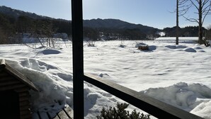 Un paysage enneigé avec un chalet en bois et une vue dégagée sur les montagnes.