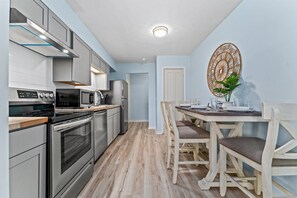 Une cuisine moderne dotée d’appareils électroménagers en acier inoxydable, un coin repas avec des chaises en bois et un élément décoratif mural.