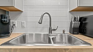 Una cucina moderna con un lavello in acciaio inossidabile, una macchina da caffè e un portacoltelli.
