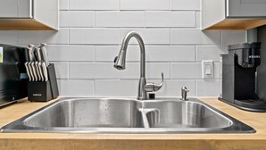 Una cucina moderna con lavello in acciaio inox, una macchina per il caffè e un portacoltelli.