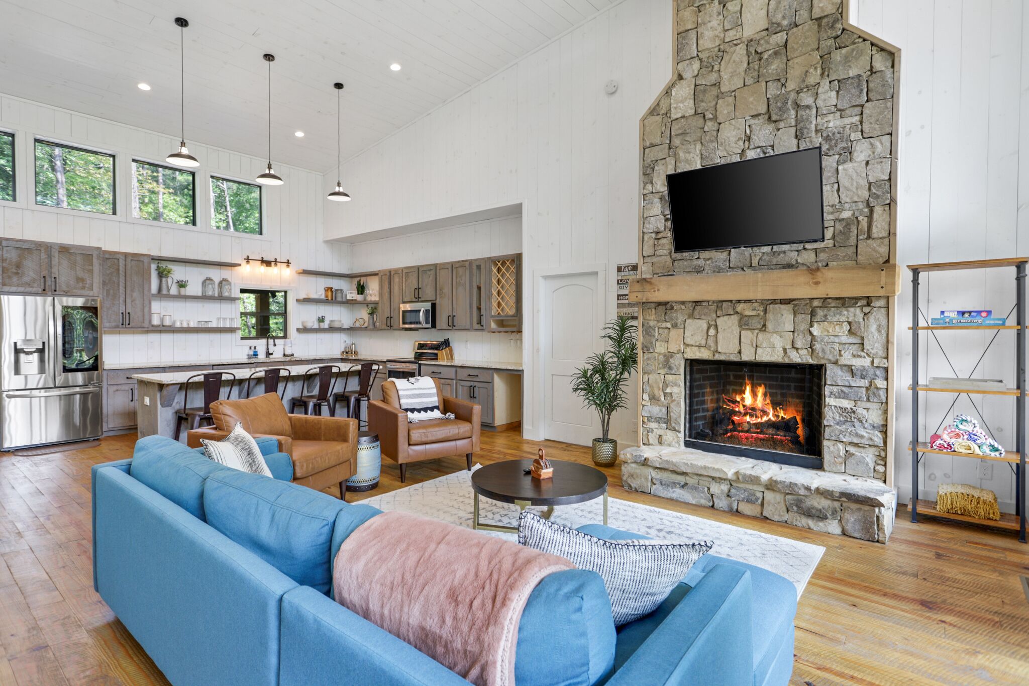 A spacious living area with a blue sofa, a fireplace, and a kitchen in the background.