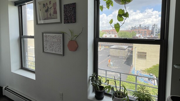 Una habitación con un ventanal grande, un radiador y varias plantas en macetas.