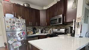 Una cocina moderna con armarios de madera oscura, electrodomésticos de acero inoxidable y una isla grande con encimera blanca.