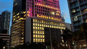 A high-rise building with a grid of windows and a pink-lit facade. - Perfect Studio 5 Icon Brickell Pool spa gym View (Miami)