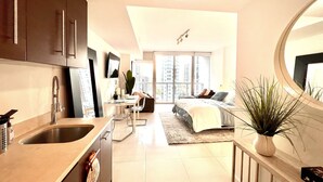 A modern apartment with a kitchen, dining area, and living room. It features a large window, a bed, and a potted plant. - Perfect Studio 5 Icon Brickell Pool spa gym View (Miami)