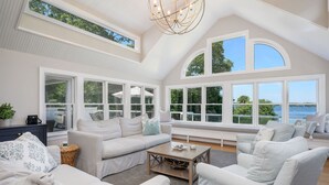 Un salon spacieux doté de grandes fenêtres, d’un plafond haut et offrant une vue sur l’extérieur.