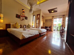 Quarto de hotel com duas camas, soalho de madeira, varanda e área de refeições.