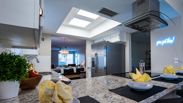 A modern kitchen with granite countertops, stainless steel appliances, and a neon sign. - 4BR w pool, shuffleboard, 2 king rooms (Chandler)
