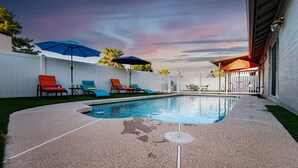 A backyard with a swimming pool, lounge chairs, and umbrellas. - 4BR w pool, shuffleboard, 2 king rooms (Chandler)