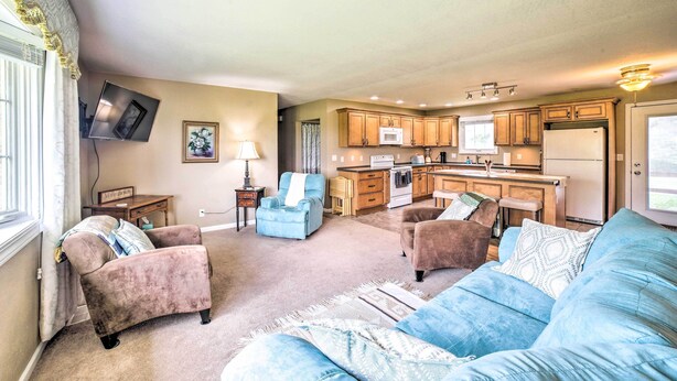 A living room with a sofa, armchairs, a television, and a kitchen in the background. - Bloomington Family Home - Private Deck & Yard (Bloomington)