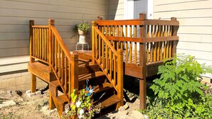 Une terrasse en bois avec un escalier menant à un espace porche.