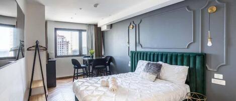A modern bedroom with a large bed, a desk, and a chair.