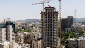 A cityscape with high-rise buildings, including a construction crane on one of the tallest structures. - Nissim (Jerusalem)