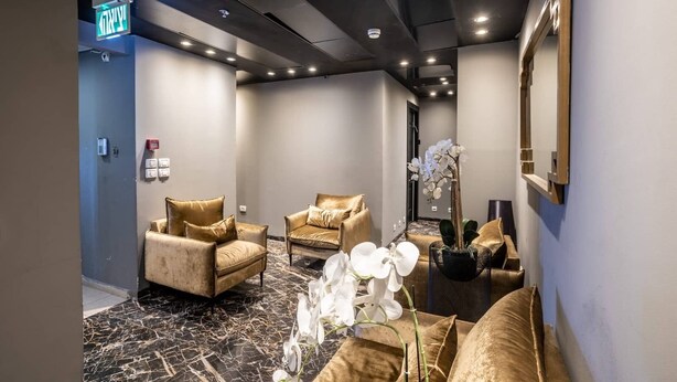 A modern spa room with two sofas, a mirror, and a vase of orchids. - Nissim (Jerusalem)