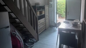 A compact kitchen with a wooden staircase, a dining table with chairs, and a door leading to a garden. - Pool pavilion in private residence (Argelès-sur-Mer)