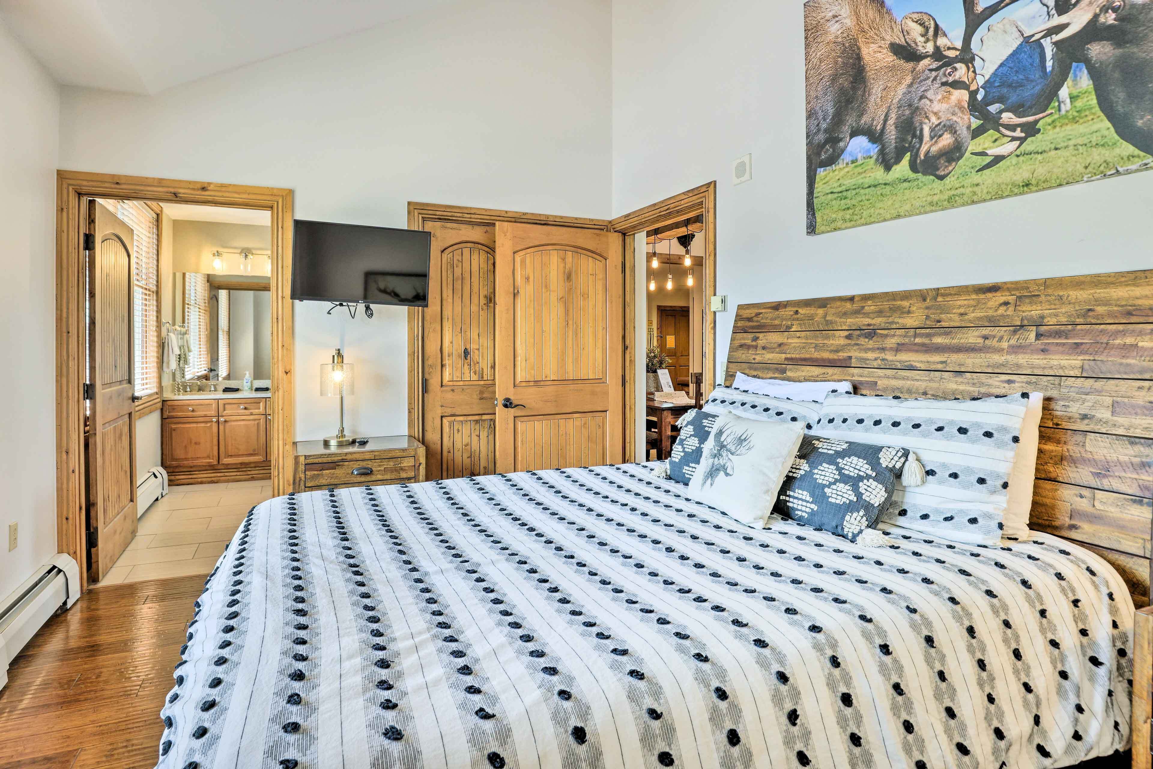 A bedroom with a large bed, wooden headboard, and a painting of moose.