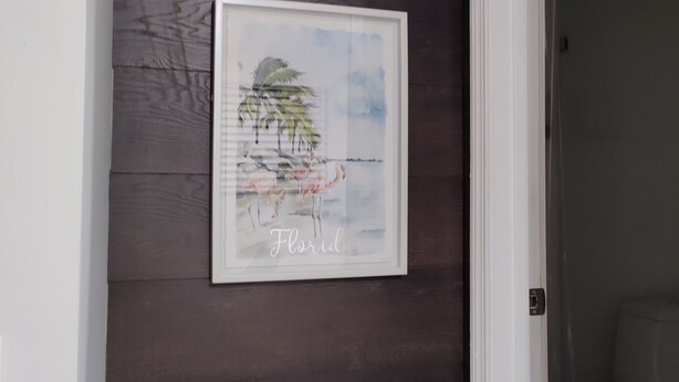 A framed artwork of a beach scene with palm trees and flamingos on a dark wooden wall. - 10 Min Brickell & Miami Beach /Parking/Wi-Fi/Grill (Miami)
